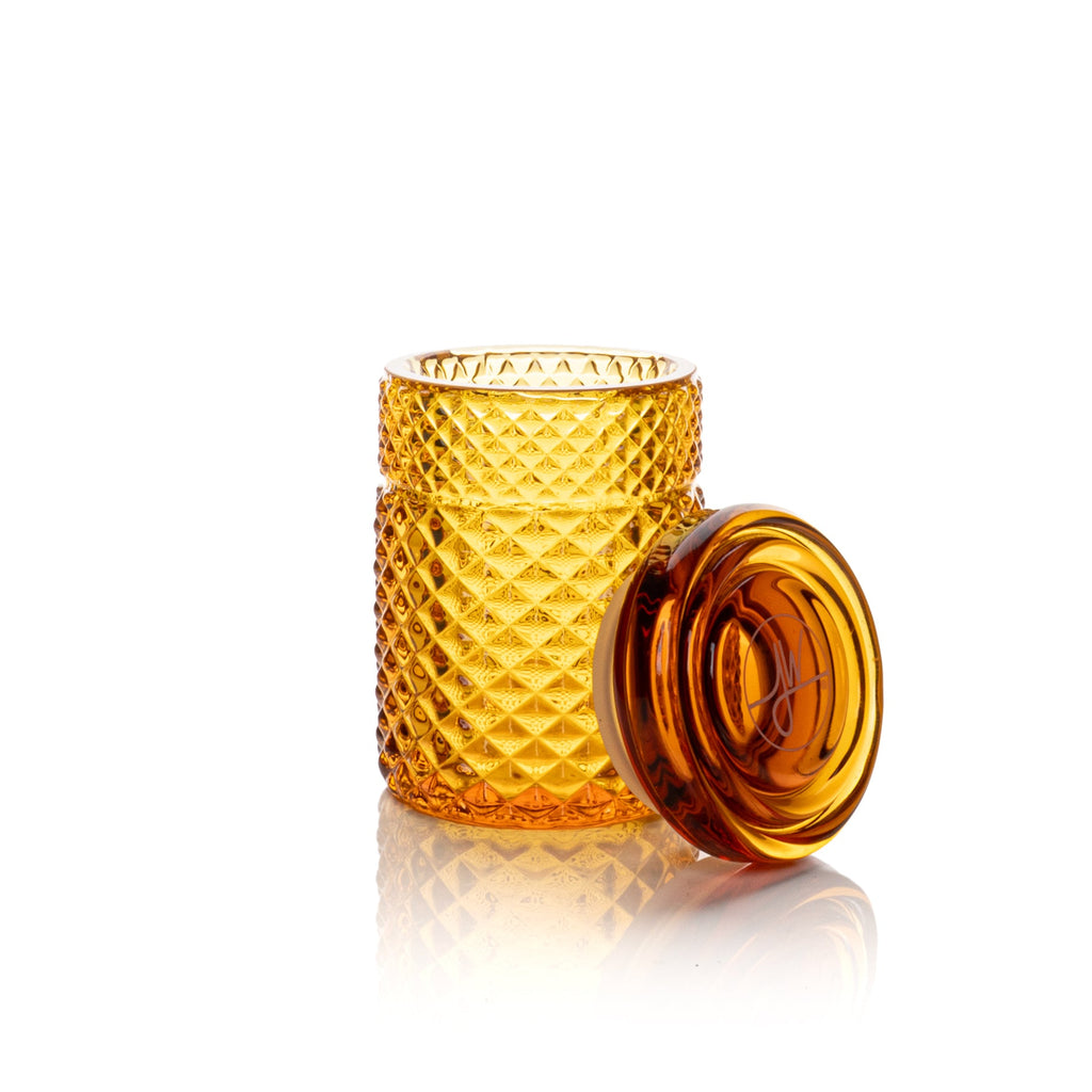 Amber glass tumbler with textured design on a white background
• 🧪 100% borosilicate glass construction
• 🔒 Silicone-sealed lid for an airtight fit
• 🌿 Designed to help preserve freshness
• 🧩 Designed to nest inside Twenties Collection ashtray
• 📏 Holds up to approx. 1/8 oz
• 🎁 Signature JW box with custom foam insert