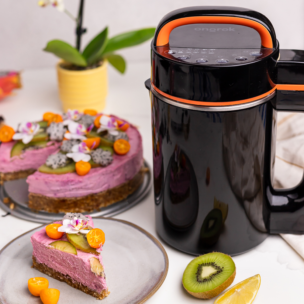 Black and orange kitchen appliance on a table with desserts and a plant in the background