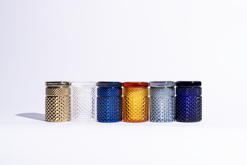 Set of six textured jars in various colors on a white background