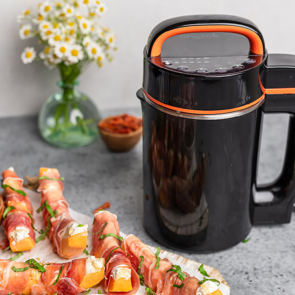 Black and orange food dehydrator on a table with wrapped meat and flowers in the background
