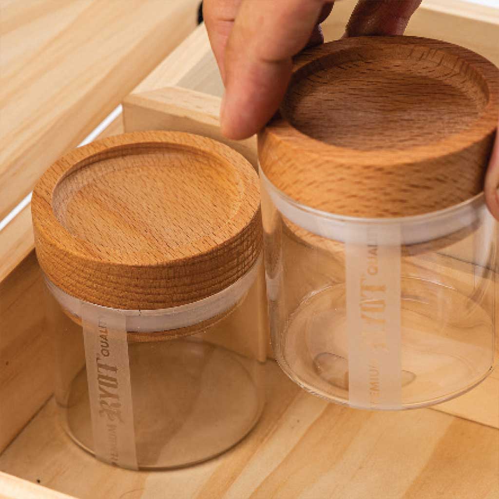 Two glass jars with wooden lids on a wooden surface