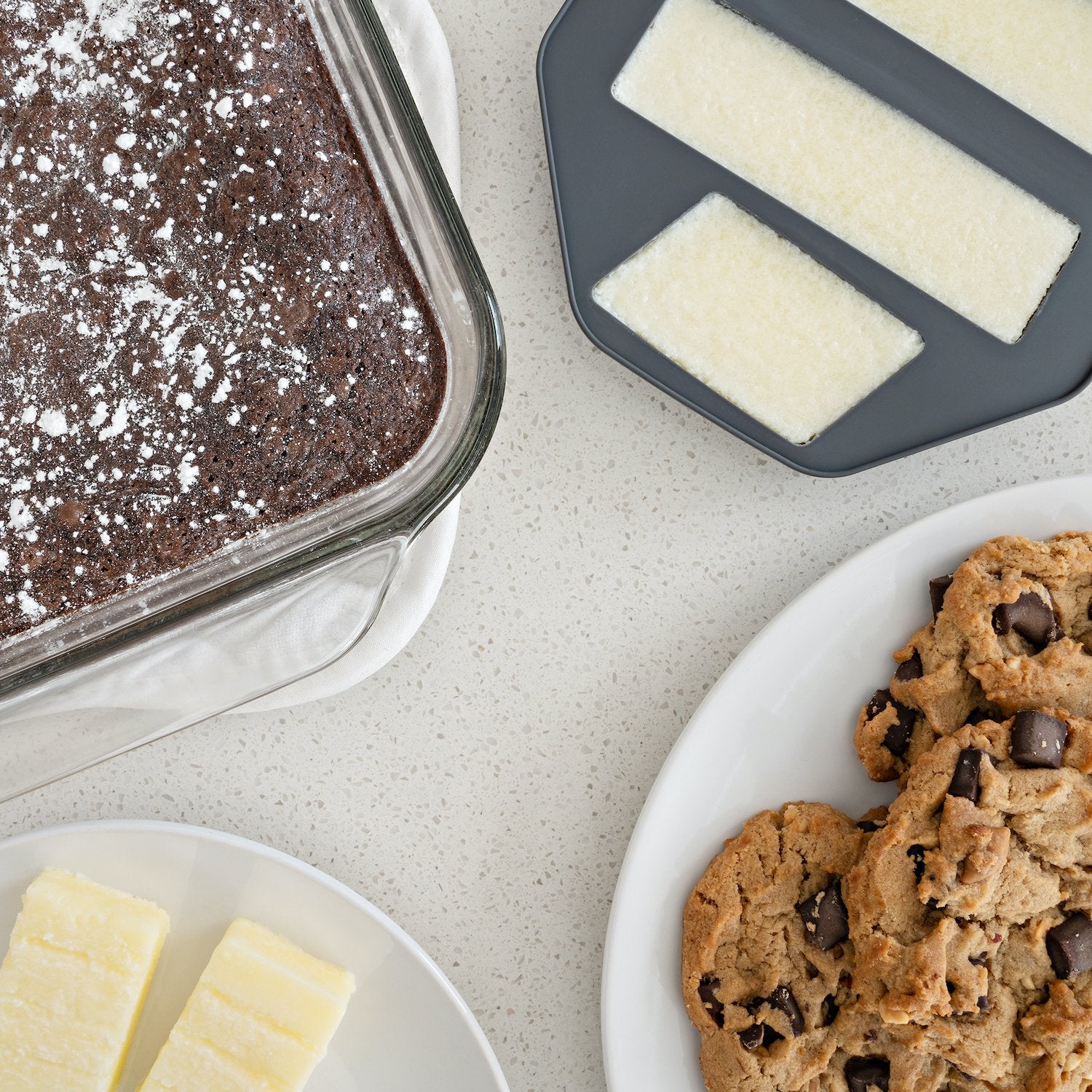 Chocolate cake, butter, and cookies on a light gray surface
