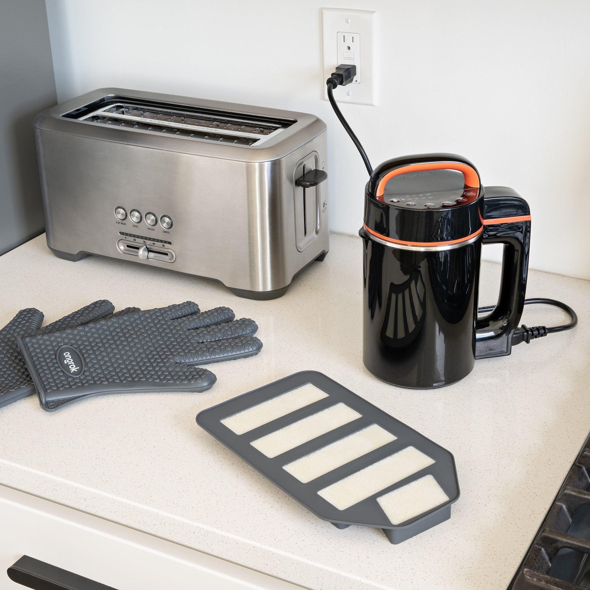 Kitchen items including a toaster, kettle, gloves, and a tray on a countertop.